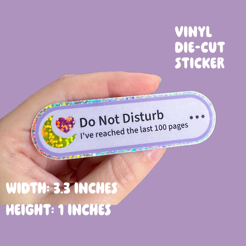 May include: A rectangular vinyl die-cut sticker with rounded edges, featuring a light purple border and a holographic finish. It displays a yellow crescent moon, a purple heart, and the text: Do Not Disturb I've reached the last 100 pages.
