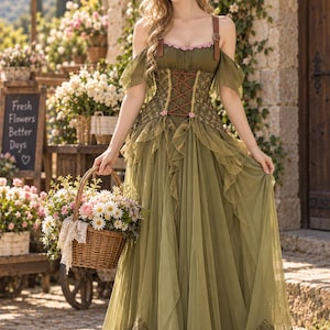 Può includere: Un abito lungo color verde oliva con corpetto in stile corsetto con allacciatura marrone, maniche trasparenti che scendono sulle spalle, gonna in tulle con volant e un ampio orlo in pizzo. L'abito è abbinato a un cesto in vimini intrecciato.