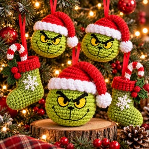 Pode incluir: Três ornamentos de crochê em forma de personagem verde com olhos amarelos e gorros de Papai Noel vermelhos, e duas meias de Natal de crochê verdes com flocos de neve brancos, punhos vermelhos e bengalas doces.