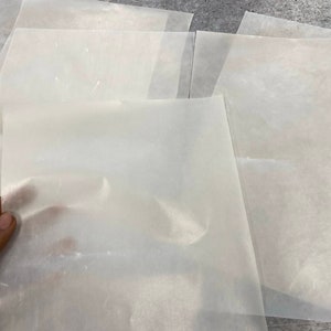 May include: A stack of translucent white sheets of parchment paper.