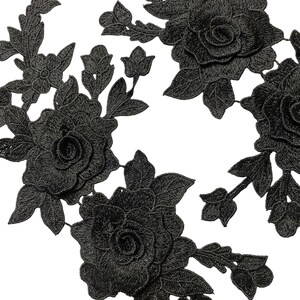May include: Close-up of black floral lace appliques. The appliques feature detailed embroidered roses, buds, and leaves. The lace is intricately designed with a textured appearance, ideal for embellishing garments or crafts.