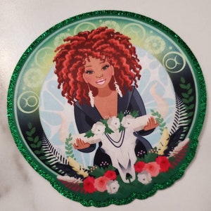 May include: A green glitter-edged circular sticker with a colorful illustration of a woman with red curly hair holding a white skull with flowers. The woman is wearing a black dress and has a pearl necklace. The sticker has a green, blue, and white background with a Taurus zodiac symbol.