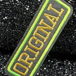 May include: A black and green embroidered patch with the word "ORIGINAL" in gold thread.