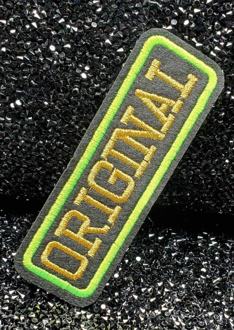 May include: A black and green embroidered patch with the word "ORIGINAL" in gold thread.