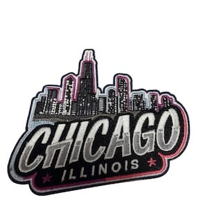 May include: An embroidered patch featuring a black and grey Chicago skyline silhouette above the text CHICAGO in bold grey letters, with the word ILLINOIS and two small pink stars below, all outlined in a thick black and pink border.