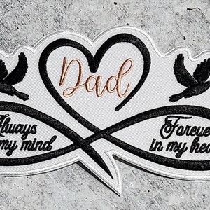 May include: Embroidered patch with a white background, black border, and black text. The design includes a heart shape with the word "Dad" in gold script, two black dove silhouettes, and the phrases "Always on my mind" and "Forever in my heart."