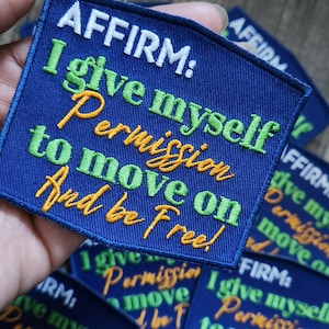 May include: A blue fabric patch with white, green, and yellow embroidery. The text reads "AFFIRM: I give myself permission to move on and be free!"