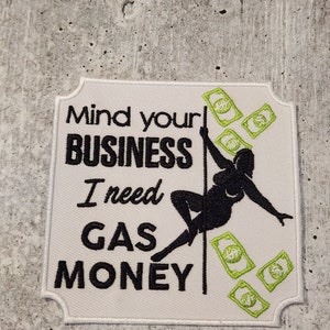 May include: White patch with black text that reads "Mind your business I need gas money". A black silhouette of a person is shown dancing on a pole with green dollar bills falling around them.