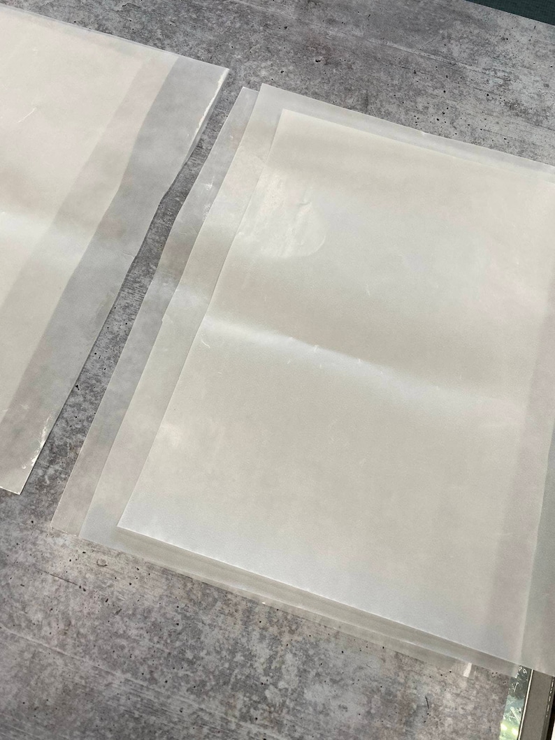 May include: A stack of four clear plastic sheets, probably for protecting surfaces or crafts.