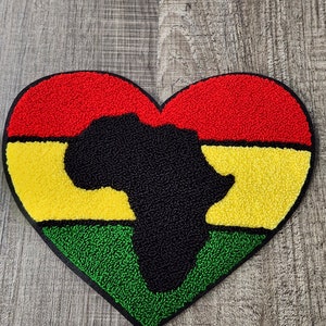 May include: A red, yellow, and green heart-shaped patch with a black outline. The center of the heart features a black silhouette of the continent of Africa.