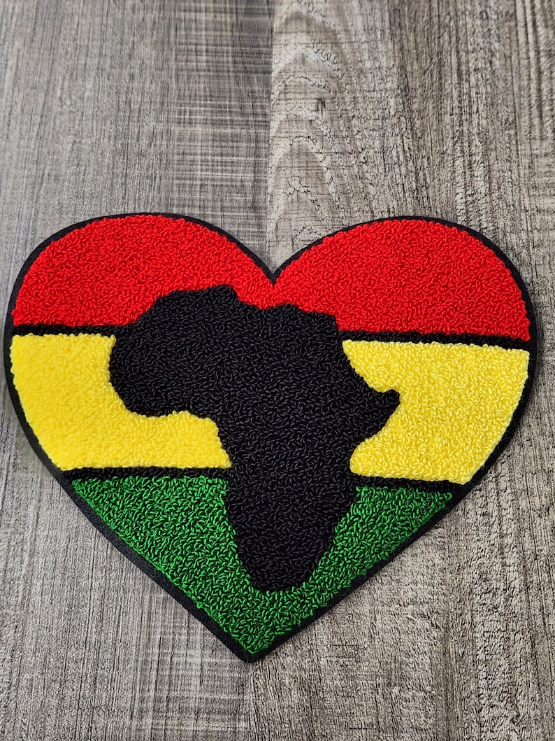 May include: A red, yellow, and green heart-shaped patch with a black outline. The center of the heart features a black silhouette of the continent of Africa.