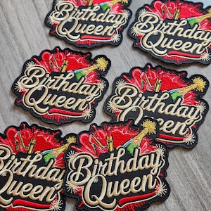 May include: Embroidered patches with the text "Birthday Queen" in gold script on a black background. The patches feature red accents, a champagne bottle, high heels, and lipstick. The patches are designed for apparel.