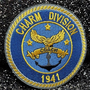 以下が含まれることがあります： 「Charm Division」と「Coach」の文字が書かれた、青と金の刺繍のワッペン。鷲とアンカーが描かれており、ワッペンの下には1941年と記されている。