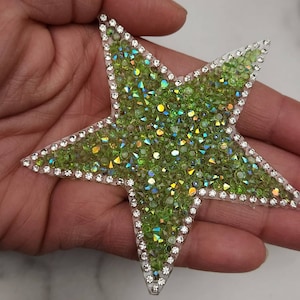 May include: A green star-shaped patch covered in iridescent green rhinestones with a clear border of smaller rhinestones.