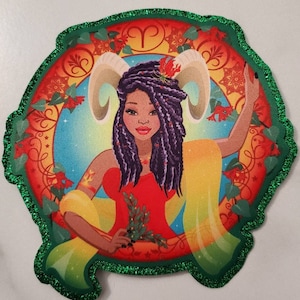 Op de afbeelding: Een kleurrijke, geïllustreerde patch met een vrouw met paars haar en ramhoorns. De achtergrond is een levendig oranje, geel en groen met een blauwe cirkel in het midden. Het symbool voor het sterrenbeeld Ram is zichtbaar in de rechterbovenhoek.