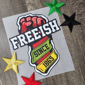May include: A red fist raised in the air with the text "FREE-ISH SINCE 1865" in white and yellow. The fist is surrounded by a green and yellow banner.