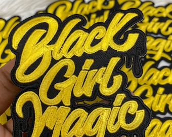 May include: Black Girl Magic embroidered patch with gold lettering on a black background. The patch has a dripping effect at the bottom.