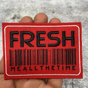 Puede incluir: Parche bordado rojo con borde blanco y texto negro que dice "FRESH" con un código de barras y las palabras "ME ALL THE TIME" debajo.