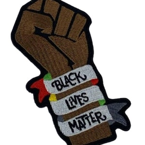 May include: Embroidered patch featuring a brown fist raised in solidarity. A white banner across the fist reads "BLACK LIVES MATTER" in black lettering. The patch has a black border and accents of red, green, and yellow.
