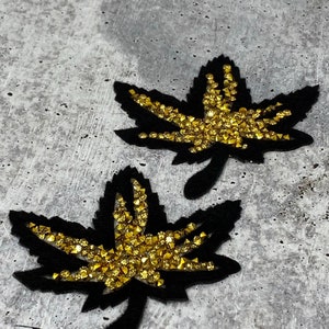 May include: Two black felt maple leaf patches with gold glitter accents.
