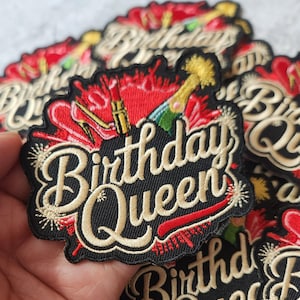 May include: Embroidered patch with the words "Birthday Queen" in gold script on a black background. The patch features red accents, a high heel, lipstick, and a champagne bottle. The patch is designed for apparel.
