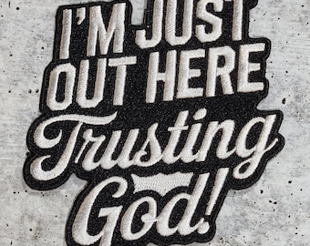Könnte beinhalten: Schwarzer und weißer gestickter Aufnäher mit dem Text "I'm just out here trusting God!" in weißer kursivschrift.