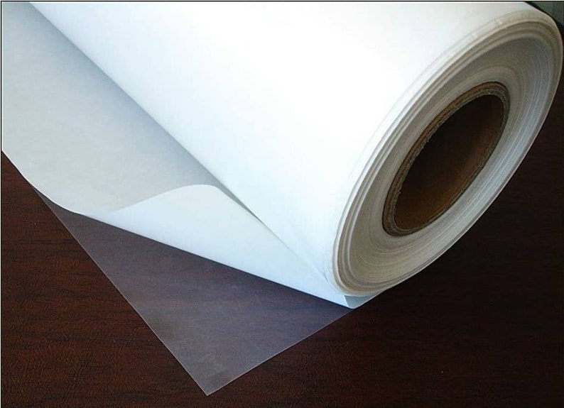 May include: A roll of white adhesive-backed vinyl, partially unrolled, revealing a clear adhesive backing. The vinyl is rolled on a cardboard core.