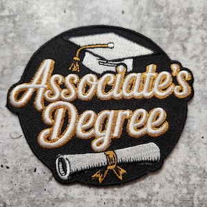 Op de afbeelding: Geborduurde patch met de woorden "Associate's Degree" in gouden letters op een zwarte achtergrond. Voorzien van een witte afstudeerhoed en een opgerold diploma met een gouden lint. Ideaal voor academische prestaties.