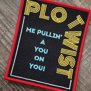 May include: Black and yellow embroidered patch with the text "PLOT TWIST" and the phrase "ME PULLIN' A YOU ON YOU!"