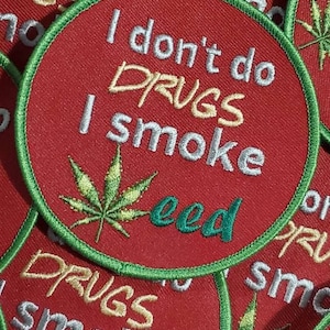 May include: A close-up of several red embroidered patches with green trim. The patches feature a marijuana leaf and the text "I don't do drugs I smoke weed".