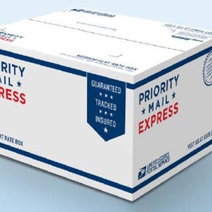 May include: A white Priority Mail Express shipping box with blue and red accents. The box is labelled "Priority Mail Express" and "Medium Flat Rate Box". The box also has a red star and the words "Guaranteed, Tracked, Insured" in a blue star.