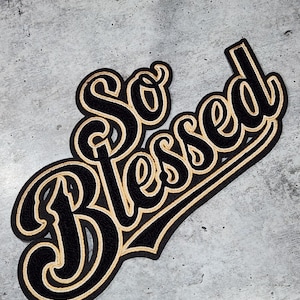 May include: A black and gold embroidered patch with the words "So Blessed" in a stylized font.
