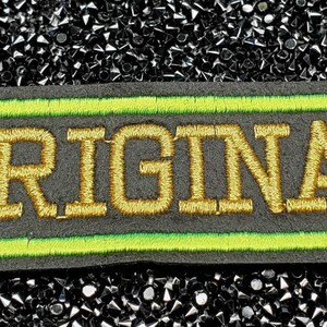 May include: A black and green embroidered patch with the word "ORIGINAL" in gold thread.
