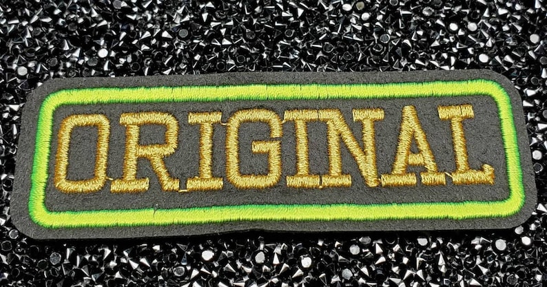 May include: A black and green embroidered patch with the word "ORIGINAL" in gold thread.