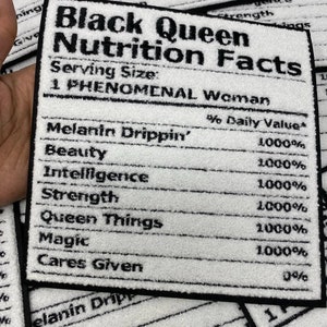 May include: A white and black rectangular patch with the text "Black Queen Nutrition Facts." The patch lists "Melanin Drippin'," "Beauty," "Intelligence," "Strength," "Queen Things," "Magic," and "Cares Given" with 1000% daily value.