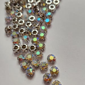 Peut inclure: Un ensemble de perles de cristal iridescentes avec des montures en métal argenté. Les perles ont un design à facettes, reflétant un spectre de couleurs. Ces perles décoratives conviennent à la fabrication de bijoux et aux projets d'artisanat.