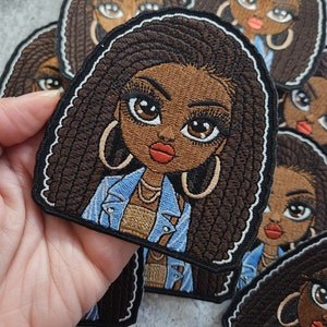 May include: A set of embroidered iron-on patches featuring a cartoon illustration of a Black woman with brown braids, wearing a blue denim jacket and gold jewelry.
