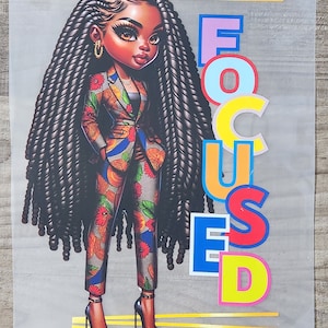 May include: A colorful illustration of a woman with long black braids wearing a patterned suit and high heels. The word "FOCUSED" is written in large, colorful letters behind her.
