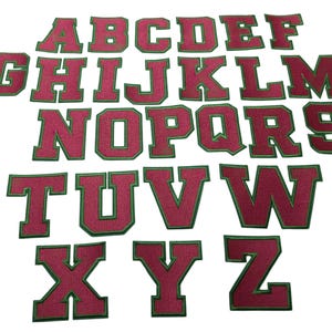 May include: A complete set of twenty-six embroidered alphabet letter patches from A to Z. Each letter features a deep magenta fabric center with a distinct green stitched border, designed in a bold, block-style varsity font for clear visibility.
