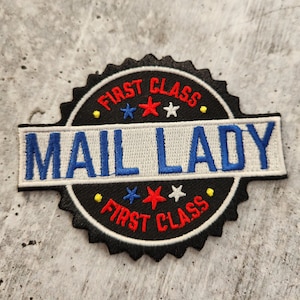 May include: Black and white embroidered patch with the text "First Class" and "Mail Lady" in blue and red stars.