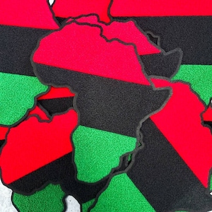 May include: Multiple fabric patches in the shape of the continent of Africa. The patches are made of red, black, and green fabric and are arranged in a layered pattern.