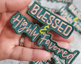 Könnte beinhalten: Ein Set aus grünen und rosafarbenen gestickten Bügeletiketten mit dem Text "Blessed & Highly Favored".
