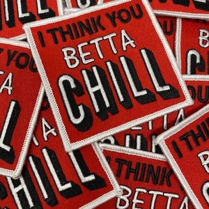 May include: A close-up of several red fabric patches with white stitching. The patches have the text "I think you betta chill" in black and white lettering.