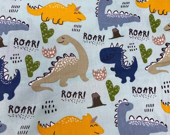 Può includere: Un tessuto blu chiaro con un motivo ripetuto di dinosauri di vari colori, tra cui giallo, verde, blu e marrone. I dinosauri sono tutti rivolti in avanti e hanno la parola "ROAR!" scritta accanto a loro.