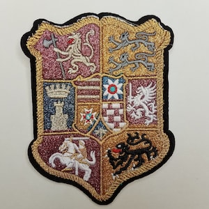 May include: A colorful embroidered patch featuring a heraldic shield with various symbols, including lions, a tower, and a griffin. The shield is surrounded by a gold border and has a black background.