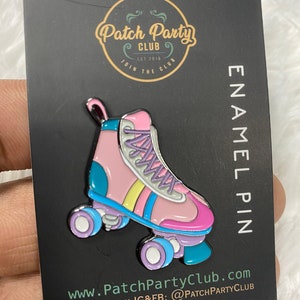 K&ouml;nnte beinhalten: Rosa und blaue Rollschuh-Emaille-Anstecknadel mit wei&szlig;en Rollen und einem gelben, rosa und blauen Streifen. Die Anstecknadel befindet sich auf einer schwarzen Karte mit dem Text "Patch Party Club Est 2018 Join the Club Enamel Pin www.PatchPartyClub.com Follow us on IG&FB: @PatchPartyClub"
