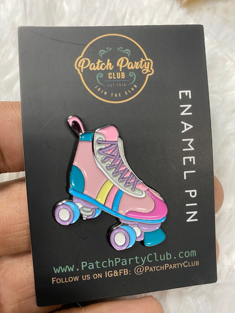 K&ouml;nnte beinhalten: Rosa und blaue Rollschuh-Emaille-Anstecknadel mit wei&szlig;en Rollen und einem gelben, rosa und blauen Streifen. Die Anstecknadel befindet sich auf einer schwarzen Karte mit dem Text "Patch Party Club Est 2018 Join the Club Enamel Pin www.PatchPartyClub.com Follow us on IG&FB: @PatchPartyClub"