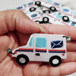 Pu&ograve; includere: Toppa ricamata bianca da stirare a forma di camioncino postale con dettagli blu e rossi. Il camioncino ha un finestrino blu, una striscia rossa e una busta blu con una lettera bianca all'interno.