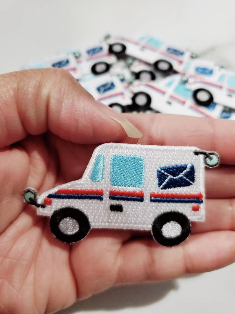 Pu&ograve; includere: Toppa ricamata bianca da stirare a forma di camioncino postale con dettagli blu e rossi. Il camioncino ha un finestrino blu, una striscia rossa e una busta blu con una lettera bianca all'interno.