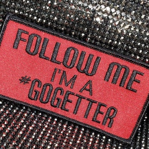 May include: Red fabric patch with black embroidered text that reads "Follow Me I'm a #GoGetter".